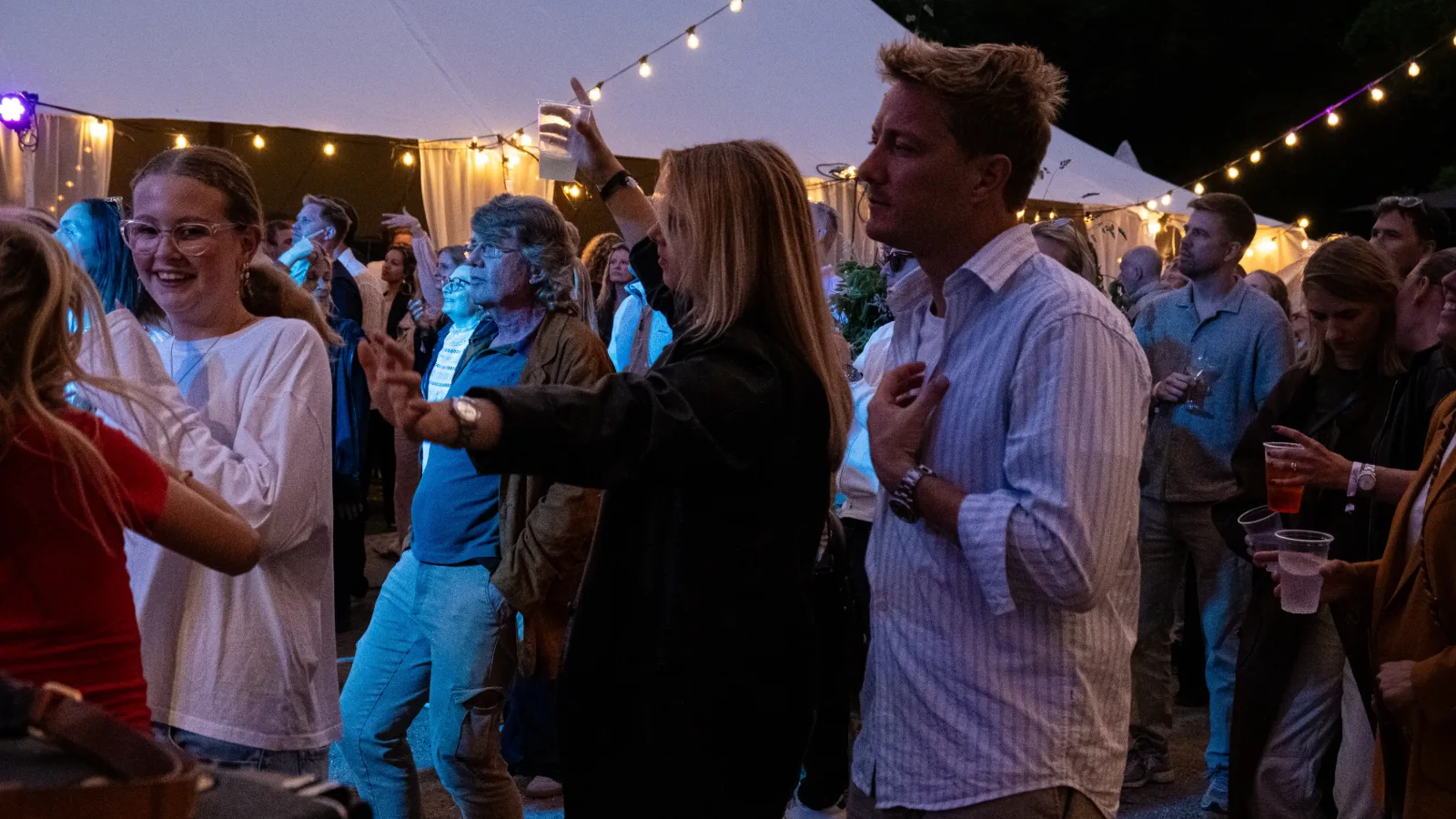 Gæster danser under lyskæder en sommeraften ved Charlottenlund Slot